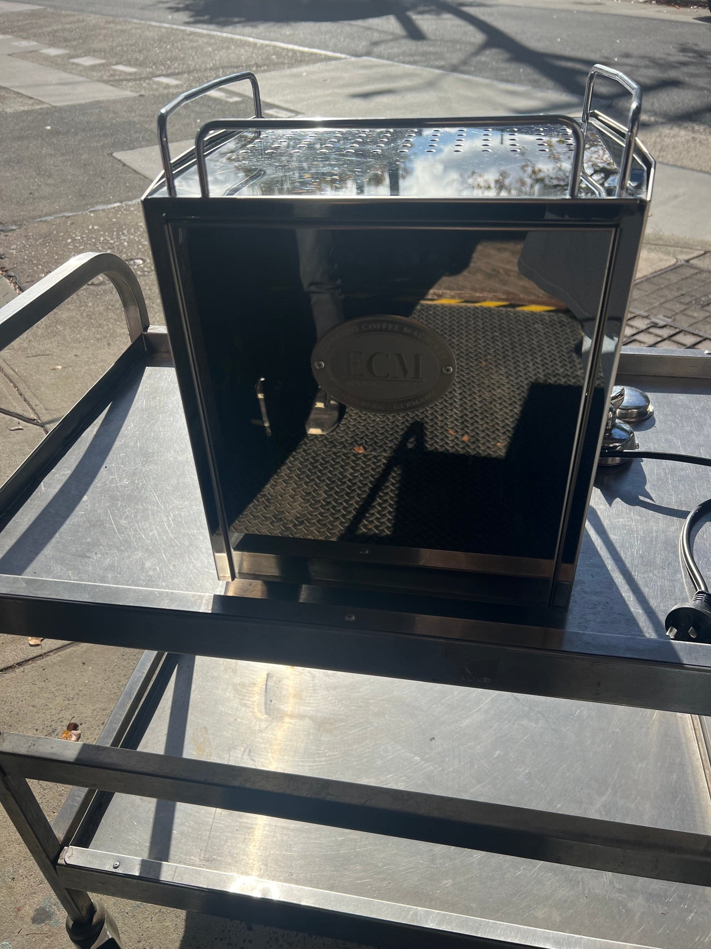 ECM Barista Coffee Machine Pre Loved on a stainless steel cart with reflections and sunlight.